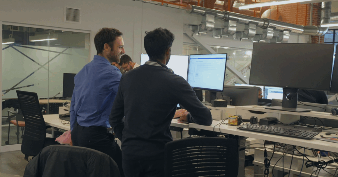 Two OPAL-RT engineers collaborating on real-time power-system simulation at dual monitors in a modern lab.