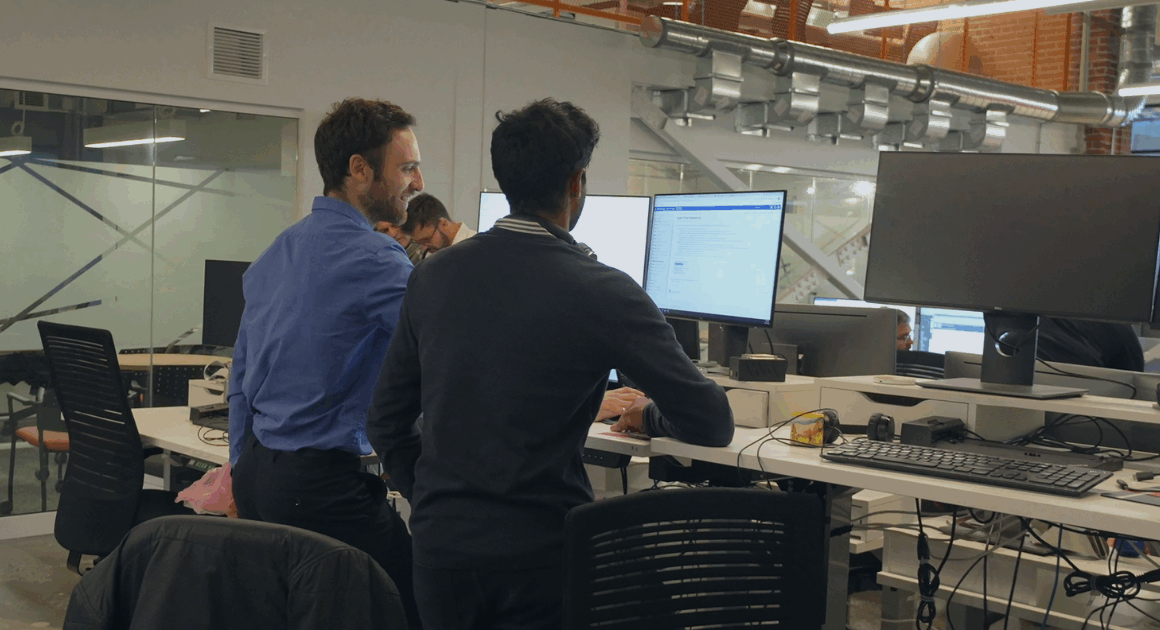 Two OPAL-RT engineers collaborating on real-time power-system simulation at dual monitors in a modern lab.