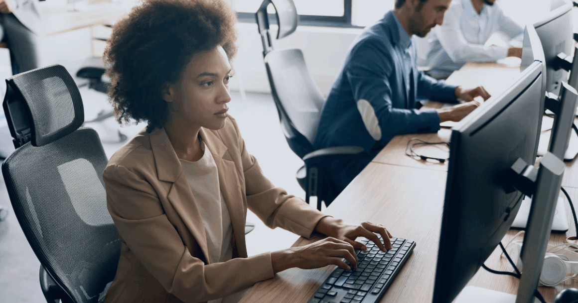 Team working at computer desks in a modern office environment, focusing on a visible workstation.