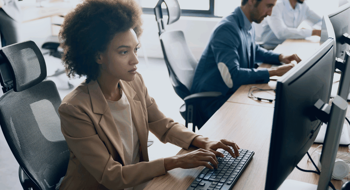 Team working at computer desks in a modern office environment, focusing on a visible workstation.