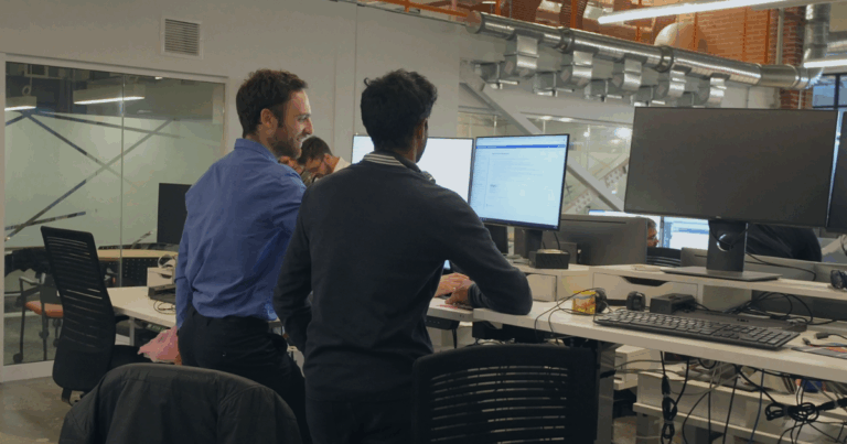 Two OPAL-RT engineers collaborating at computer monitors while testing real-time power system simulations.
