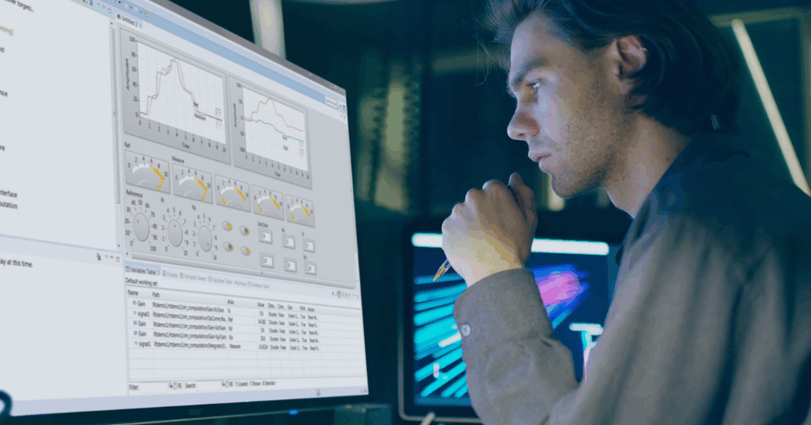 Engineer reviewing SimPowerSystems software interface on a monitor for real-time power system simulation.