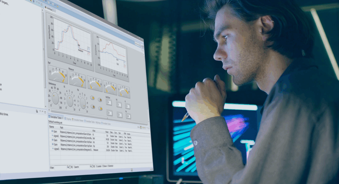 Engineer reviewing SimPowerSystems software interface on a monitor for real-time power system simulation.